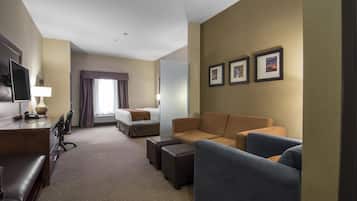 A hotel room with a bed, a desk with a chair, a sofa, and a TV.