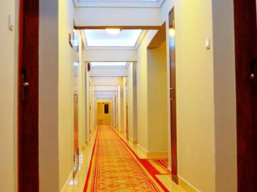 A hotel hallway with a red carpet, multiple doors, and a skylight ceiling.