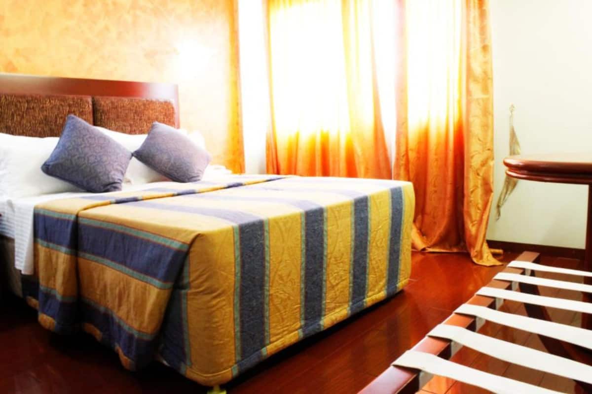 A neatly made bed with a striped bedspread, a wooden headboard, and two pillows.