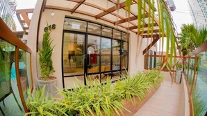 Un bâtiment moderne doté d’une façade en verre, d’une terrasse en bois et de plantes en pot.