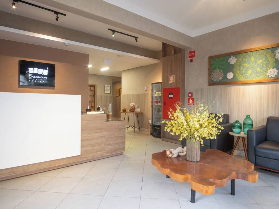 A reception area with a wooden reception desk, a coffee table with a floral arrangement, a sofa, and a wall-mounted artwork.