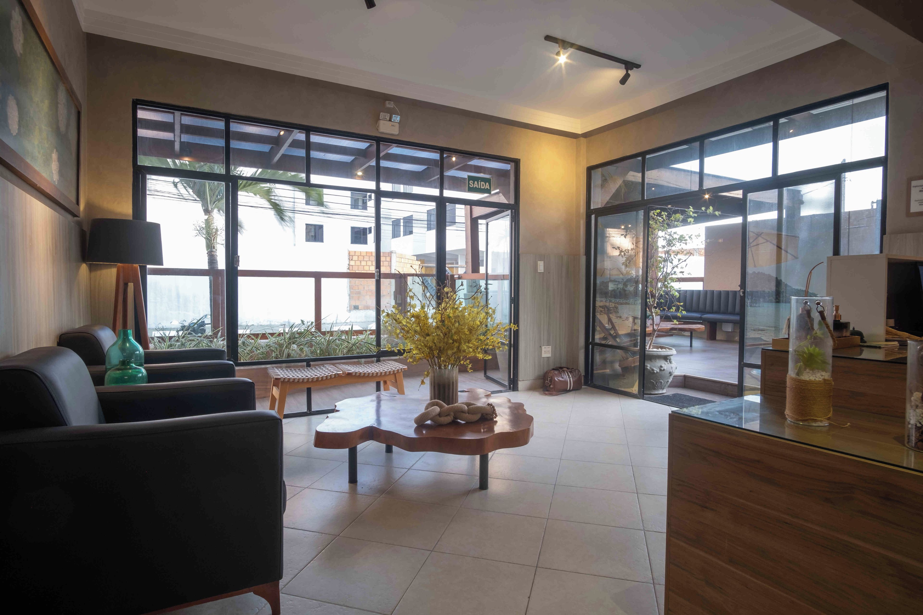 A modern living room with a sofa, a coffee table, and a large window providing a view of the outside.
