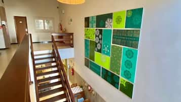 Um hall de hotel com uma escadaria, uma área de refeições e uma parede decorada com azulejos verdes e brancos.