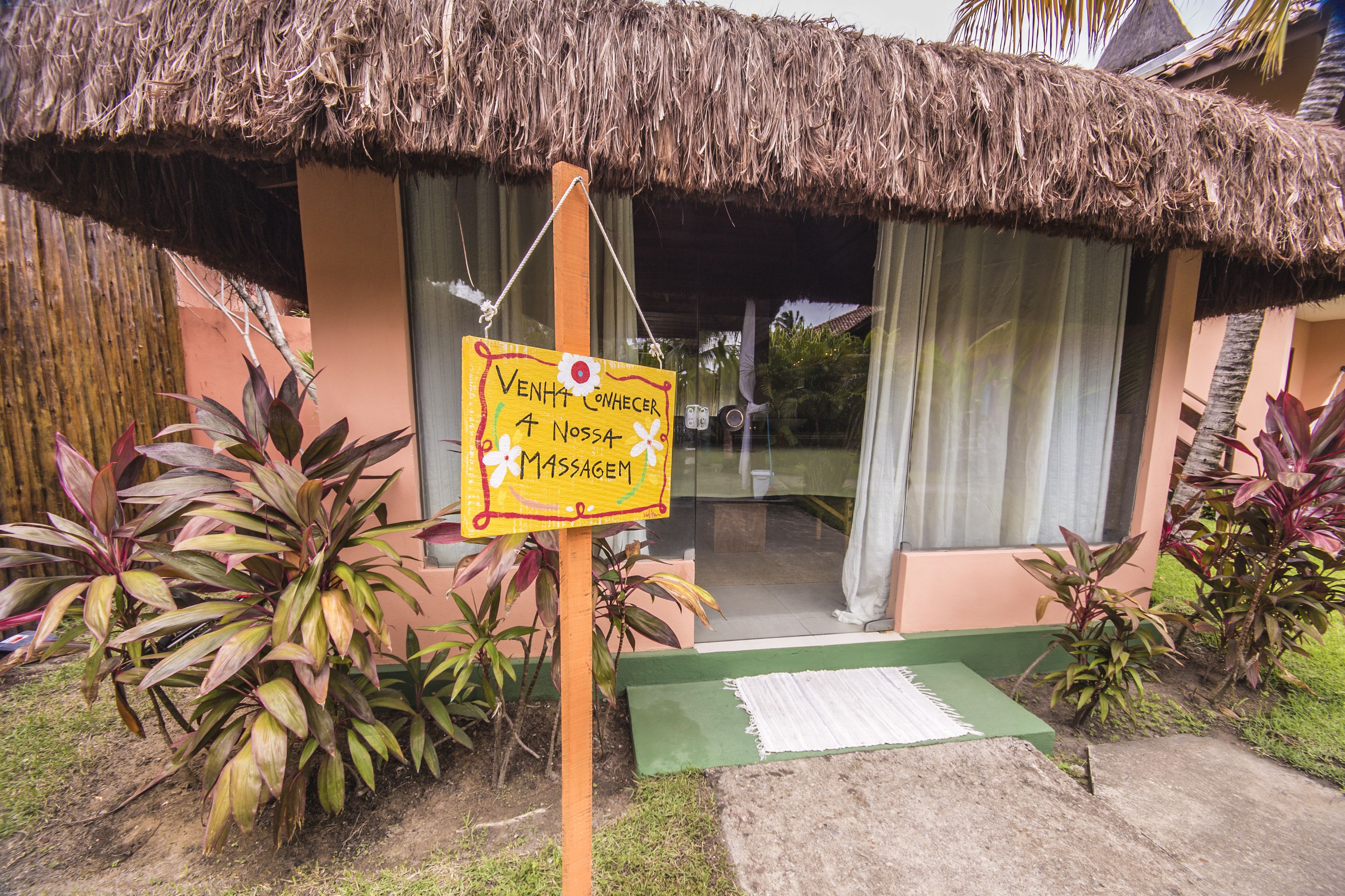 Un bâtiment doté d’un toit de chaume et d’une enseigne indiquant qu’il propose des services de massage.