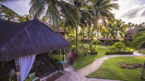 Ein Resort mit einem strohgedeckten Gebäude, einem gepflasterten Weg und üppiger Vegetation.