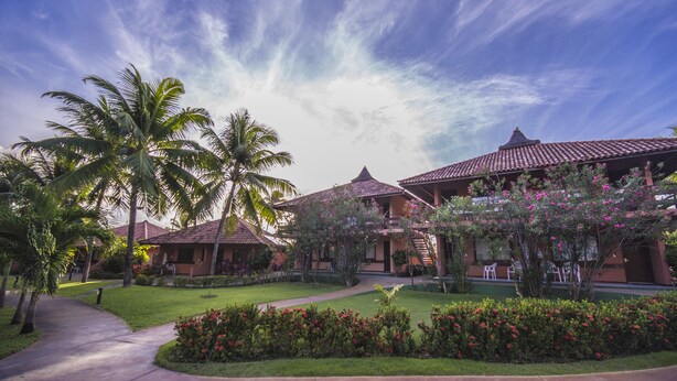 Ein Resort mit mehreren Gebäuden, Palmen und gepflegten Gärten.