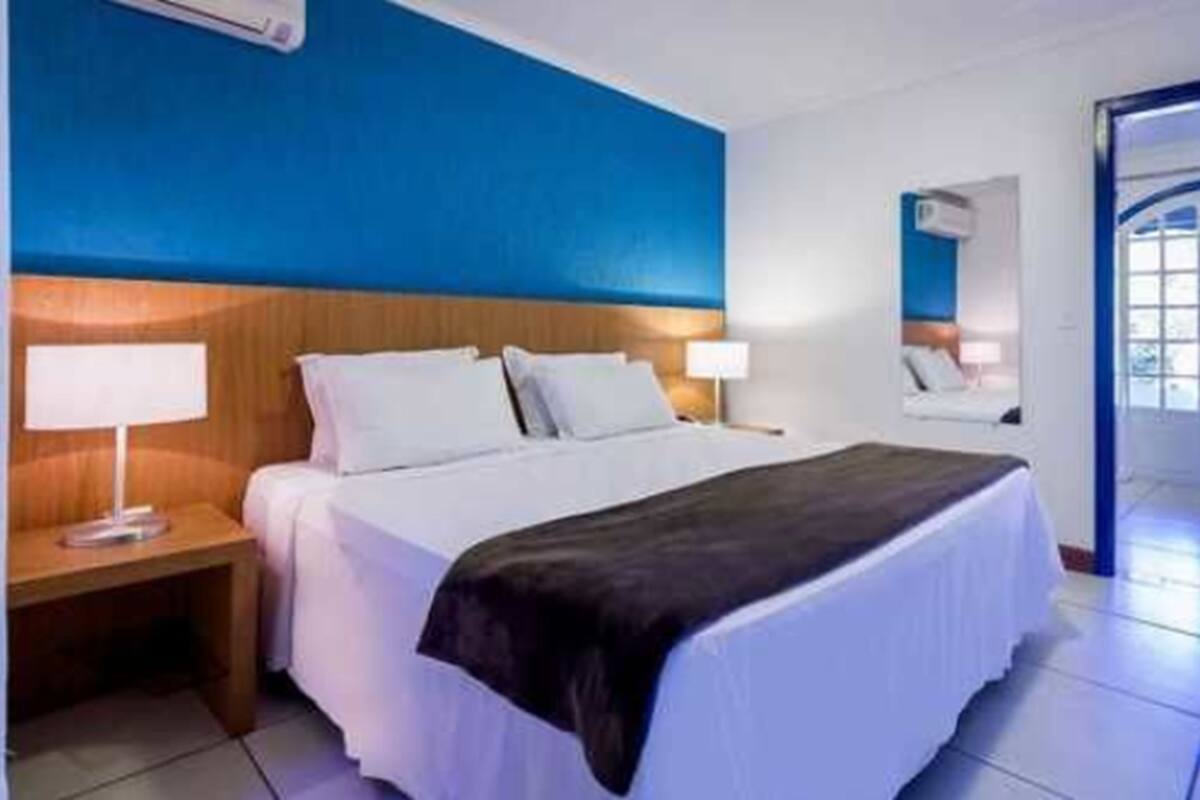 Une chambre d’hôtel avec un lit, une table de chevet et un miroir.