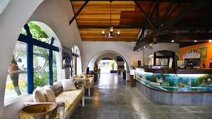 A spacious lobby with a reception desk, seating area, and large windows with tropical views. - Pousada Da Condessa (Paraty)