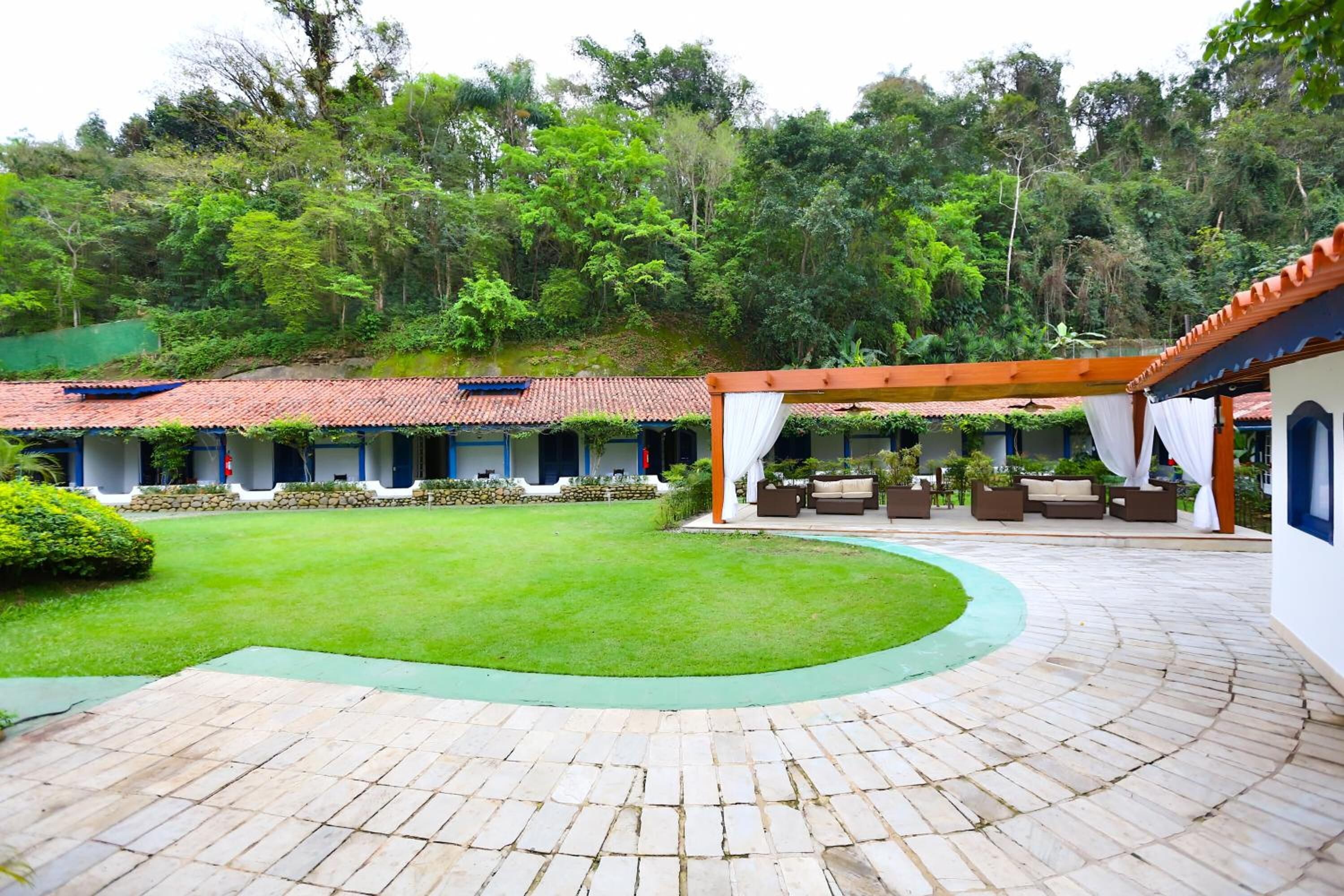 A courtyard with a paved walkway, outdoor seating, and a view of a forested hillside.