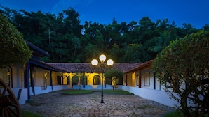 A courtyard with cobblestone flooring, a traditional building with a tiled roof, and a street lamp in the center. - Pousada Da Condessa (Paraty)
