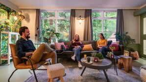 A cozy living room with a sofa, chairs, a coffee table, and potted plants. - Stayokay Arnhem - Hostel (Arnhem)