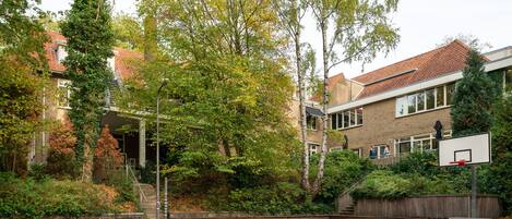 An outdoor basketball court surrounded by trees and residential buildings.