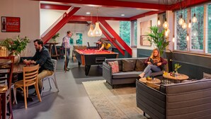 A modern indoor space with a pool table, seating areas, and a Coca-Cola sign. - Stayokay Arnhem - Hostel (Arnhem)