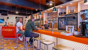 Un espace bar avec des tabourets, un comptoir et un panneau indiquant « STAYOKAY ».