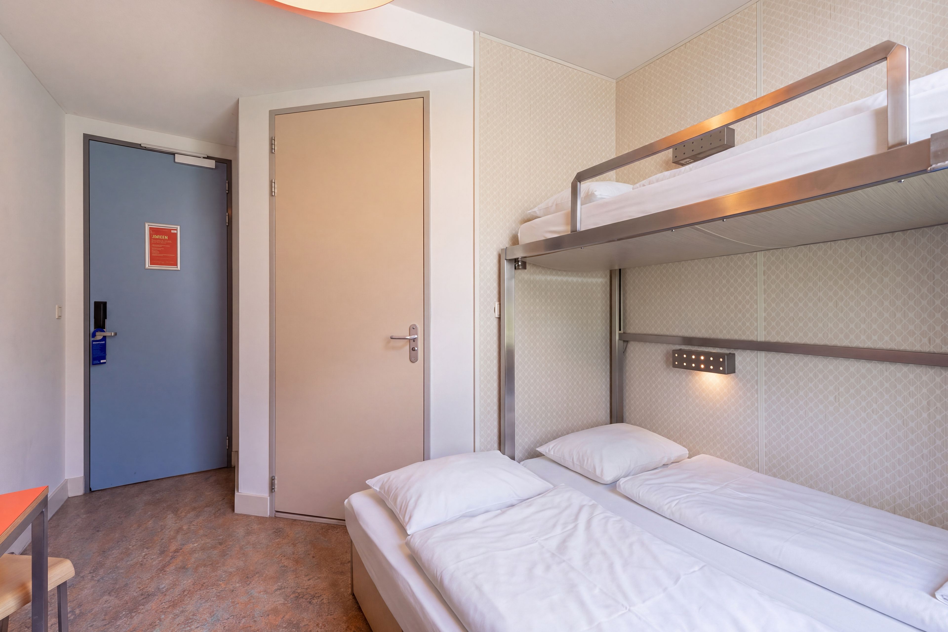 A room with a bunk bed, a desk, and a door with a sign.