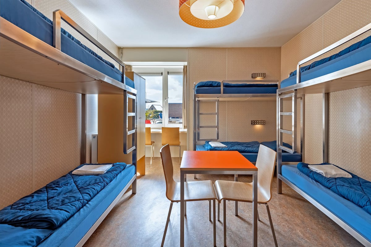 Ein kleines Zimmer mit Etagenbetten, einem Tisch und Stühlen.