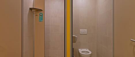 A small, enclosed bathroom with a toilet, a hand dryer, and a mirror.