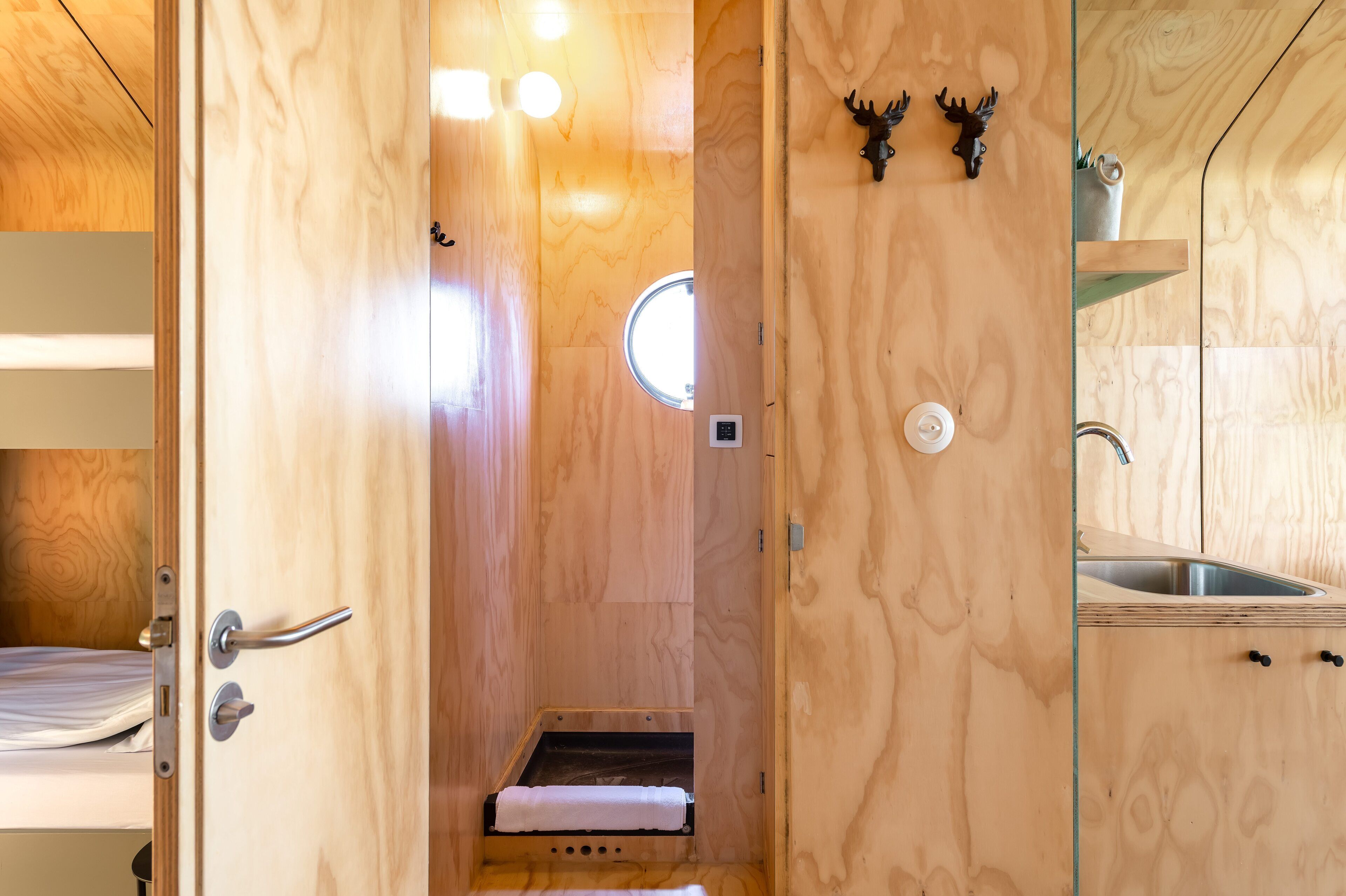 A wooden interior with a shower, a sink, and a small window.
