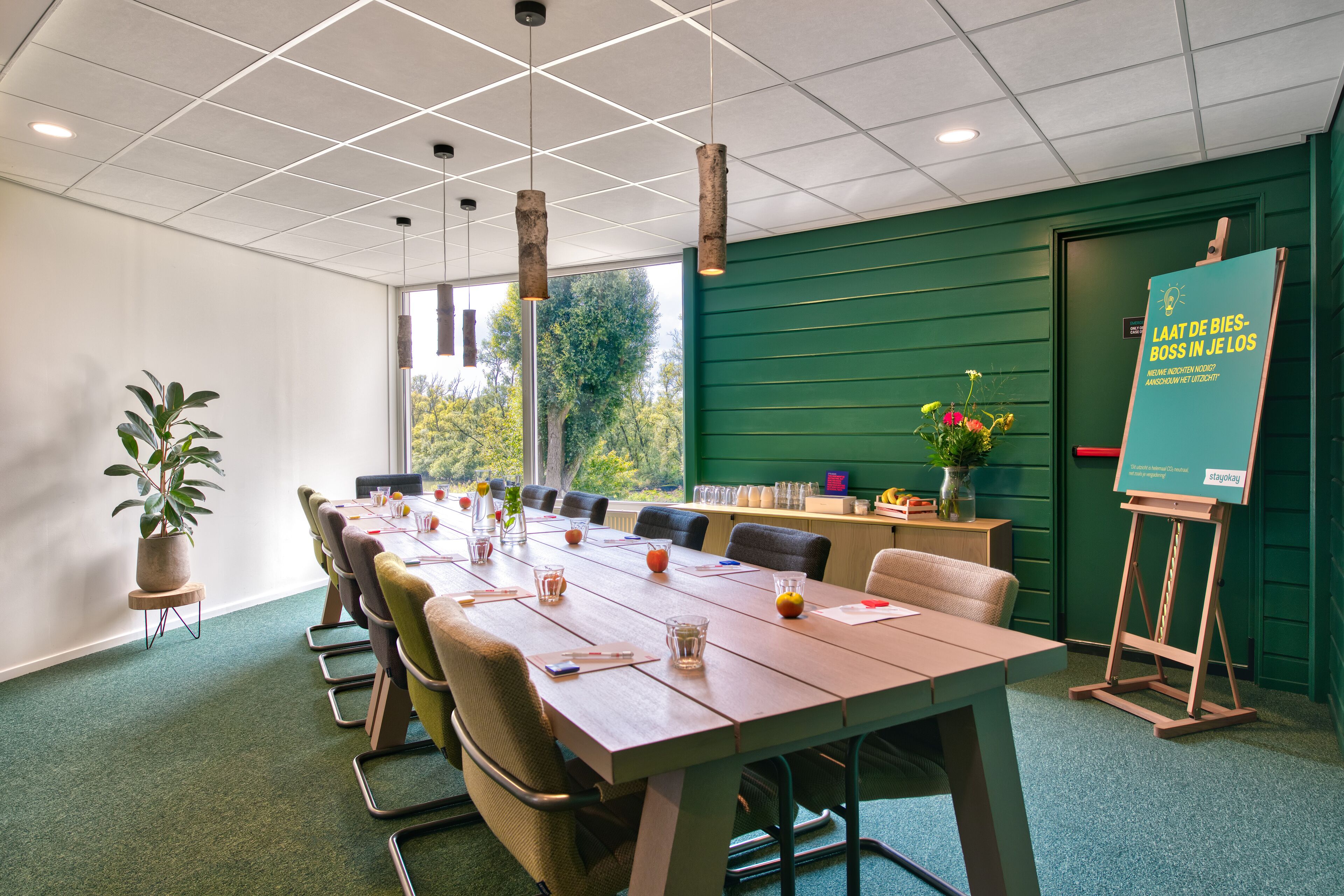 A conference room with a long table, chairs, and a green accent wall.
