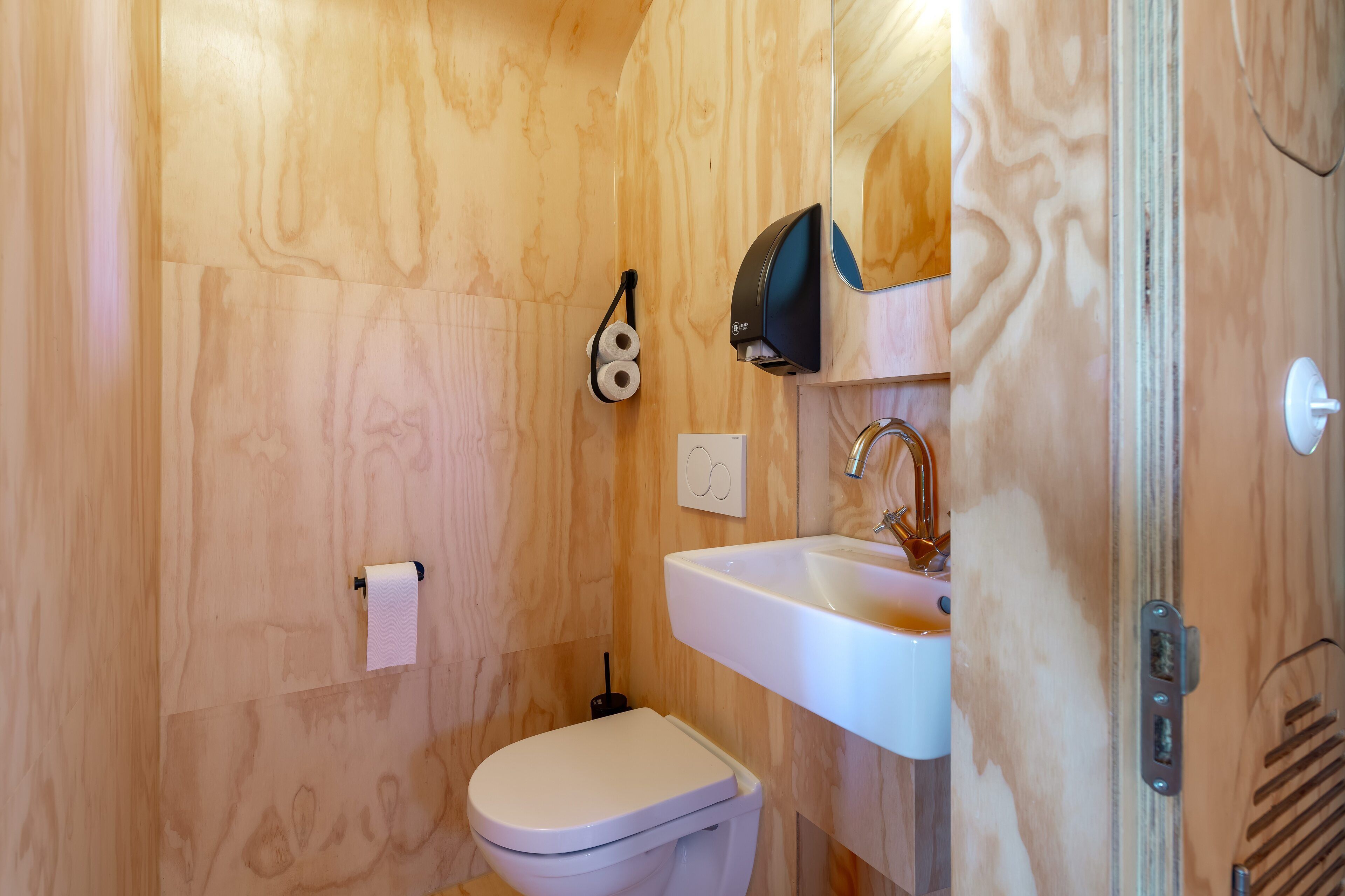 Un bagno con il water, un lavandino e un dispenser di asciugamani.