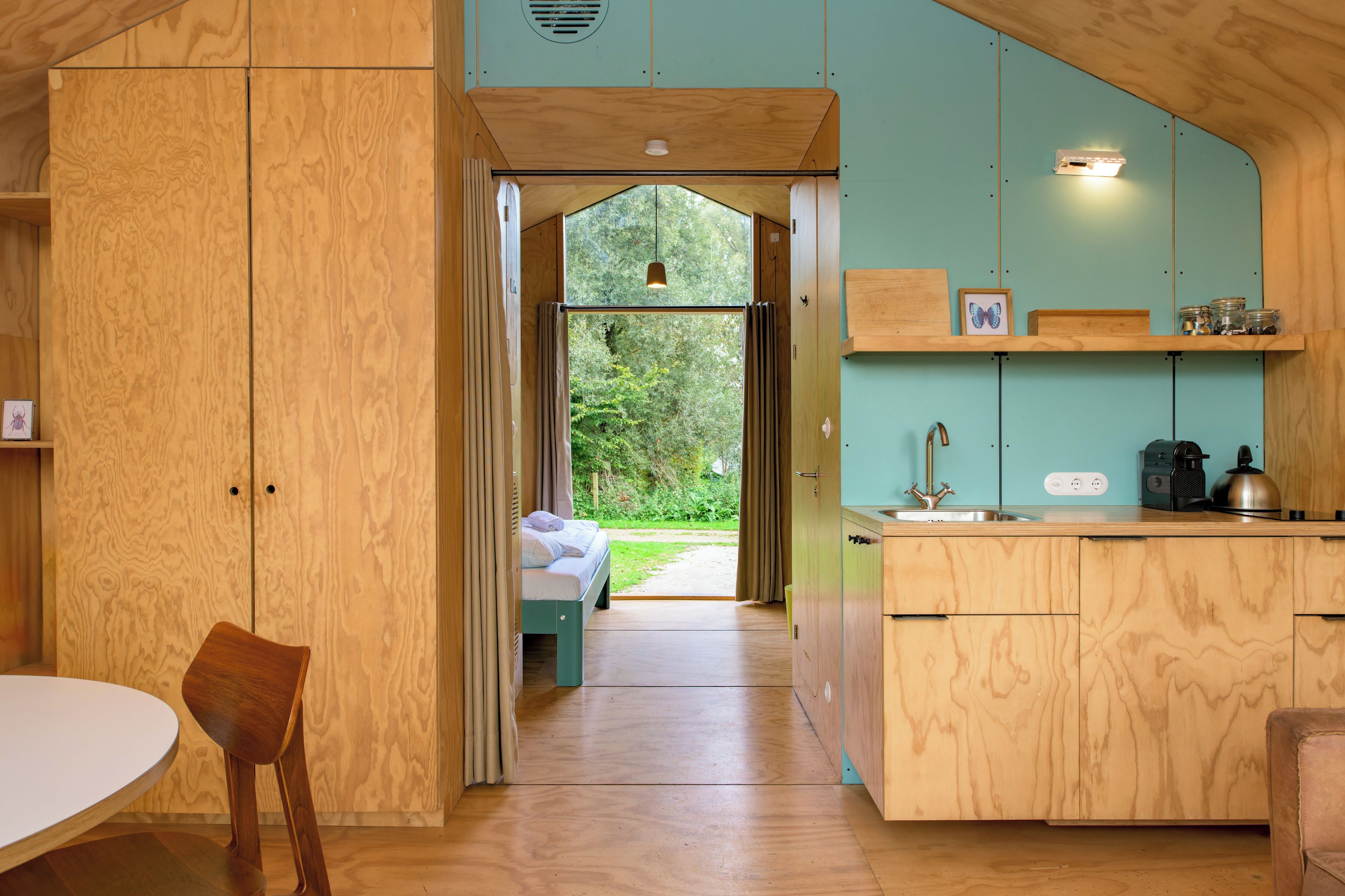 Una cocina compacta con armarios de madera, un lavamanos y una ventana que da a un jardín.