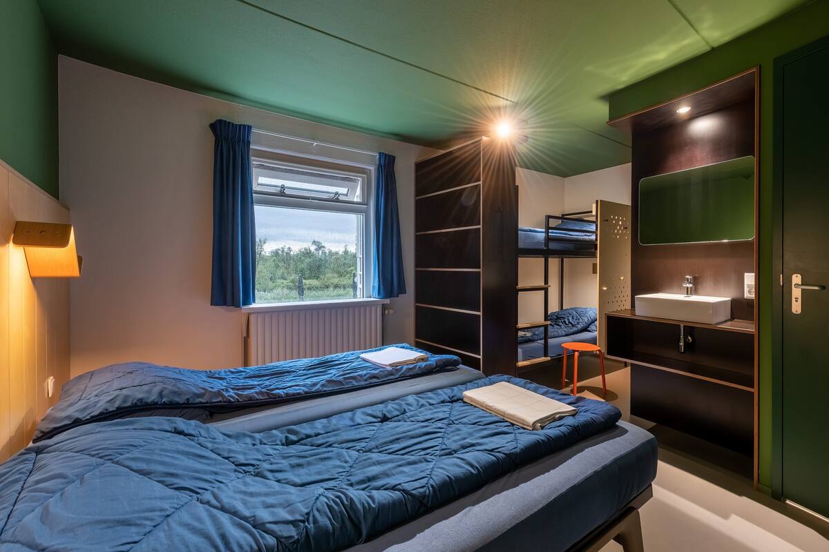 A bedroom with a bunk bed, a desk, a chair, and a window with curtains.
