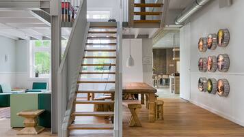 Un interior amplio con una escalera de madera, un área de comedor y una pared decorada con placas.