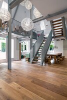 A spacious interior with a wooden staircase, high ceilings, and hanging spherical light fixtures.