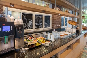 A buffet area with a coffee machine, various food items, and a chalkboard with motivational quotes.