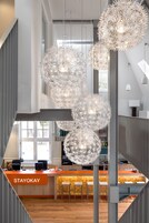 A modern interior with a central bar area, multiple hanging light fixtures, and a staircase.