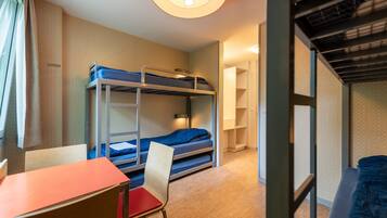 A bunk bed room with a desk and chair, a window with curtains, and a door leading to another room.