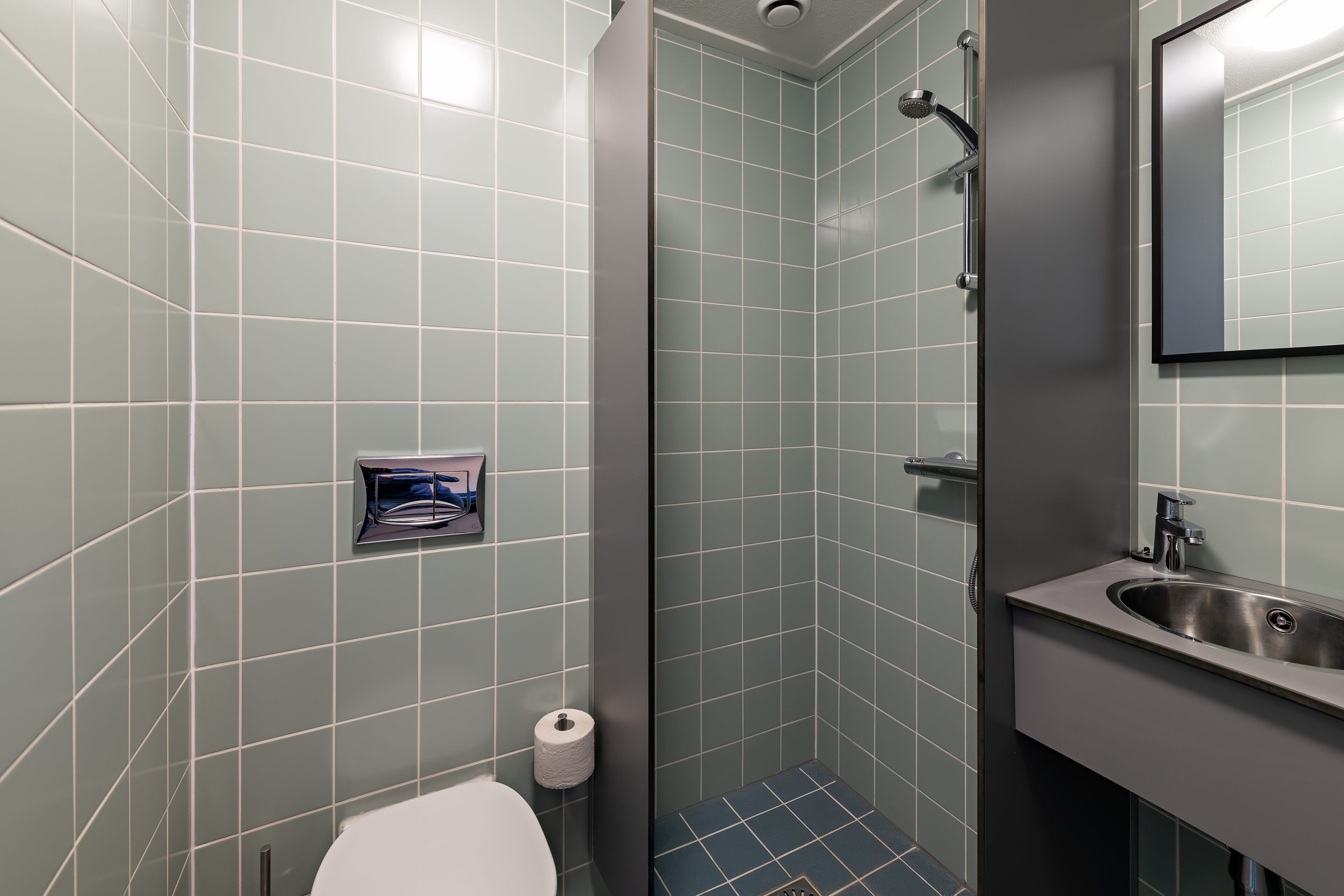 Un baño con inodoro, lavamanos y zona de ducha.