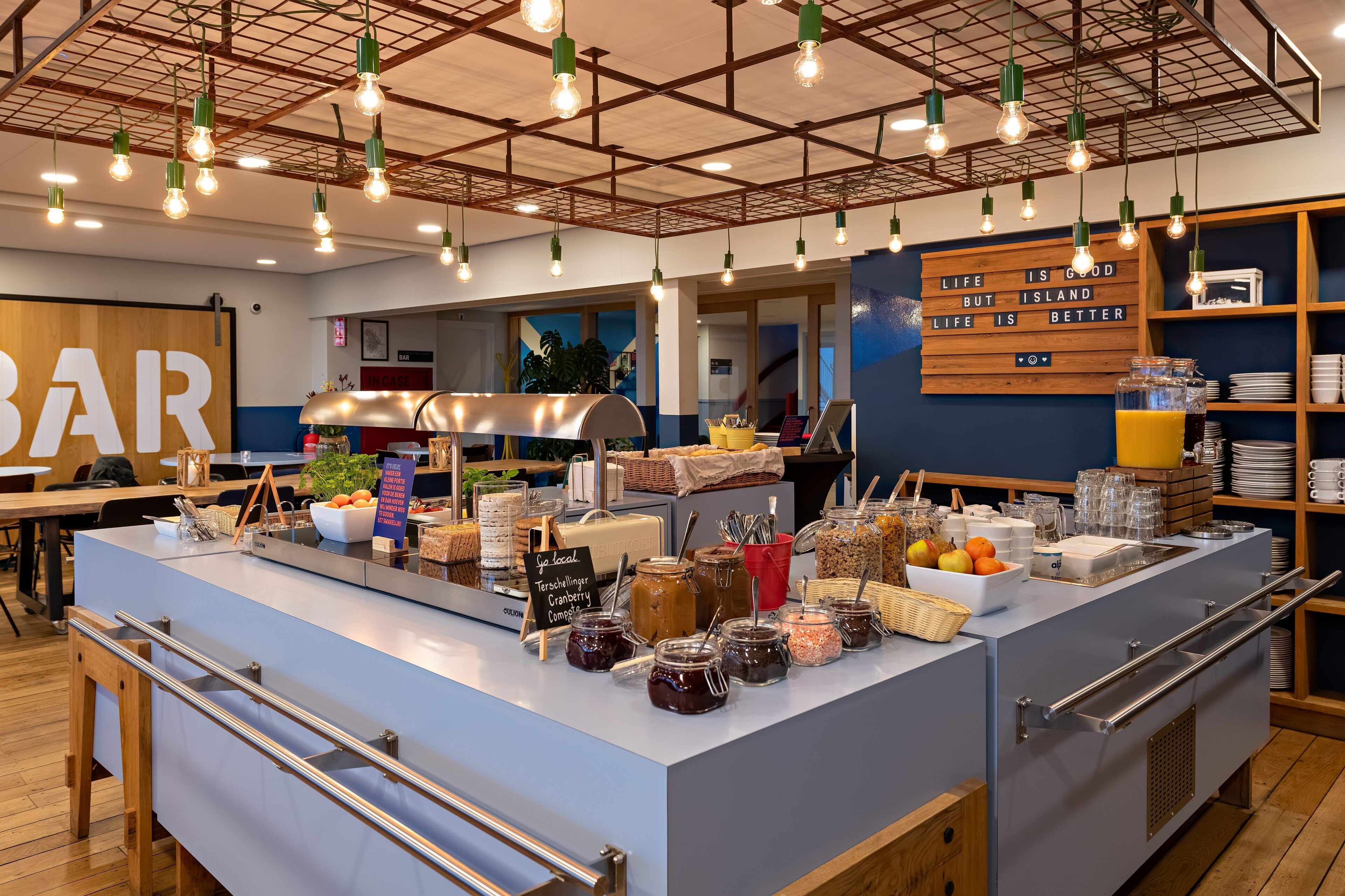 A breakfast bar with various food items and a sign that reads "Life is good but life is better."