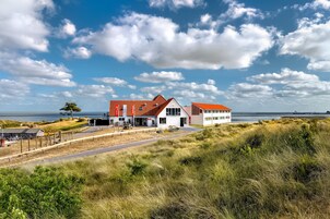 Una casa costera con techo rojo, paredes blancas y vista al mar.