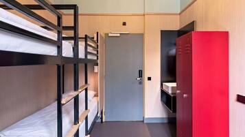 Habitación con literas, un armario rojo y una puerta.