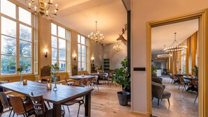 Un amplio comedor con mesas y sillas de madera, ventanas grandes y luminarias decorativas.