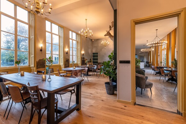 Un amplio comedor con mesas y sillas de madera, ventanas grandes y luminarias decorativas.