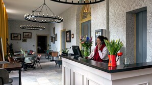 Zona de recepción de un hotel con diseño moderno, que incluye un mostrador de recepción, una araña y obras de arte enmarcadas en las paredes.