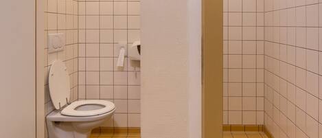 Un baño pequeño con un inodoro, un dispensador de toallas y un dispensador de servilletas de papel.
