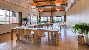 Une salle de conférence spacieuse, dotée de longues tables, de chaises et de lampes orange suspendues au plafond.