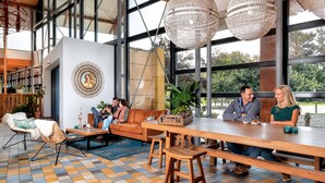 Un espace intérieur vaste et lumineux, avec une grande table en bois, des sièges confortables et de grandes fenêtres donnant sur l’extérieur.