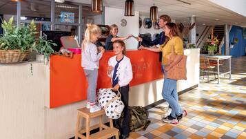 Een receptie met een receptiebalie, een klok en een trap op de achtergrond.