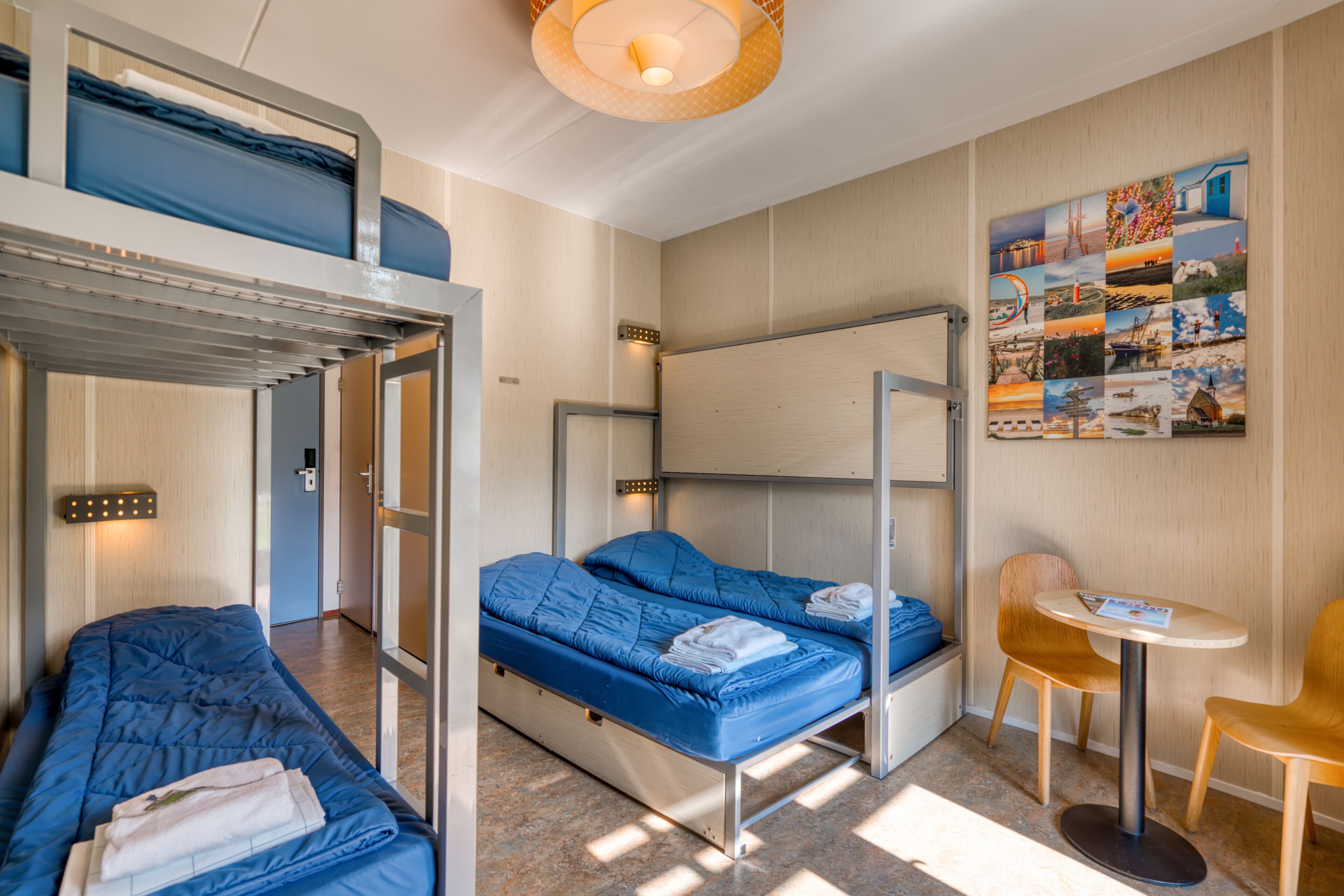 Une chambre d’hôtel compacte avec des lits superposés, une petite table et une œuvre d’art accrochée au mur.
