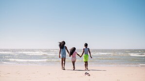 Trois personnes se promènent sur une plage.