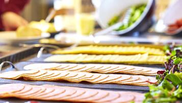 Ein Buffet mit verschiedenen Speisen, darunter Aufschnitt und Gemüse.