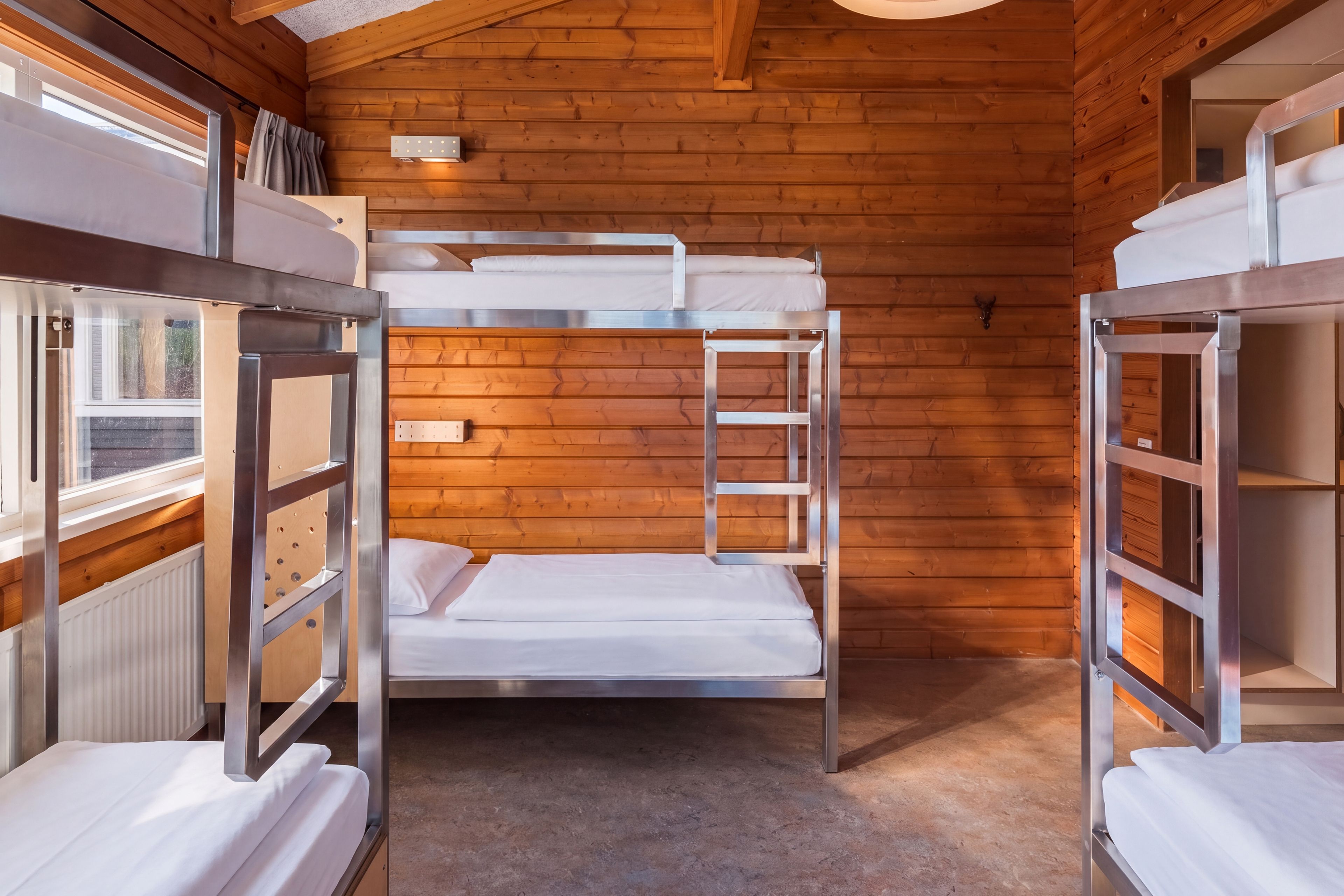 A bunk bed room with wooden walls and a window.