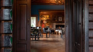 Una habitación con piso de madera, una chimenea, una zona de comedor con sillas y un cuadro en la pared.
