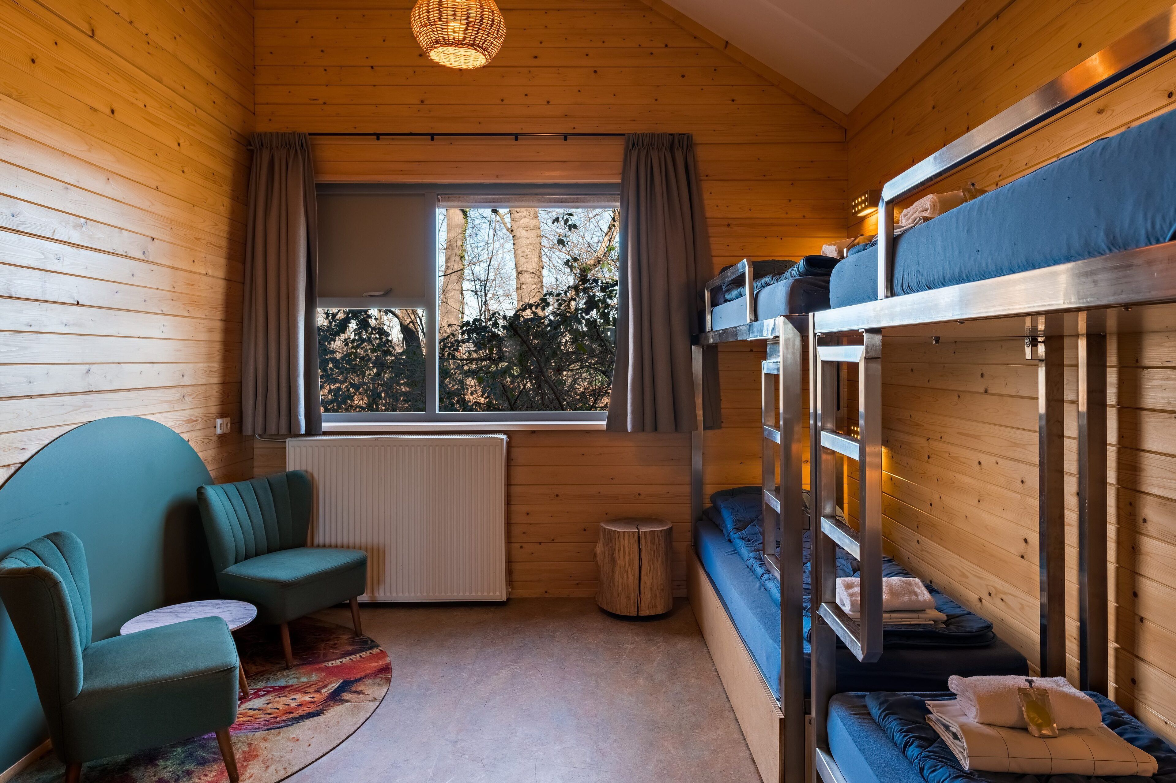 A cozy cabin with bunk beds, a sofa, and a window with curtains.