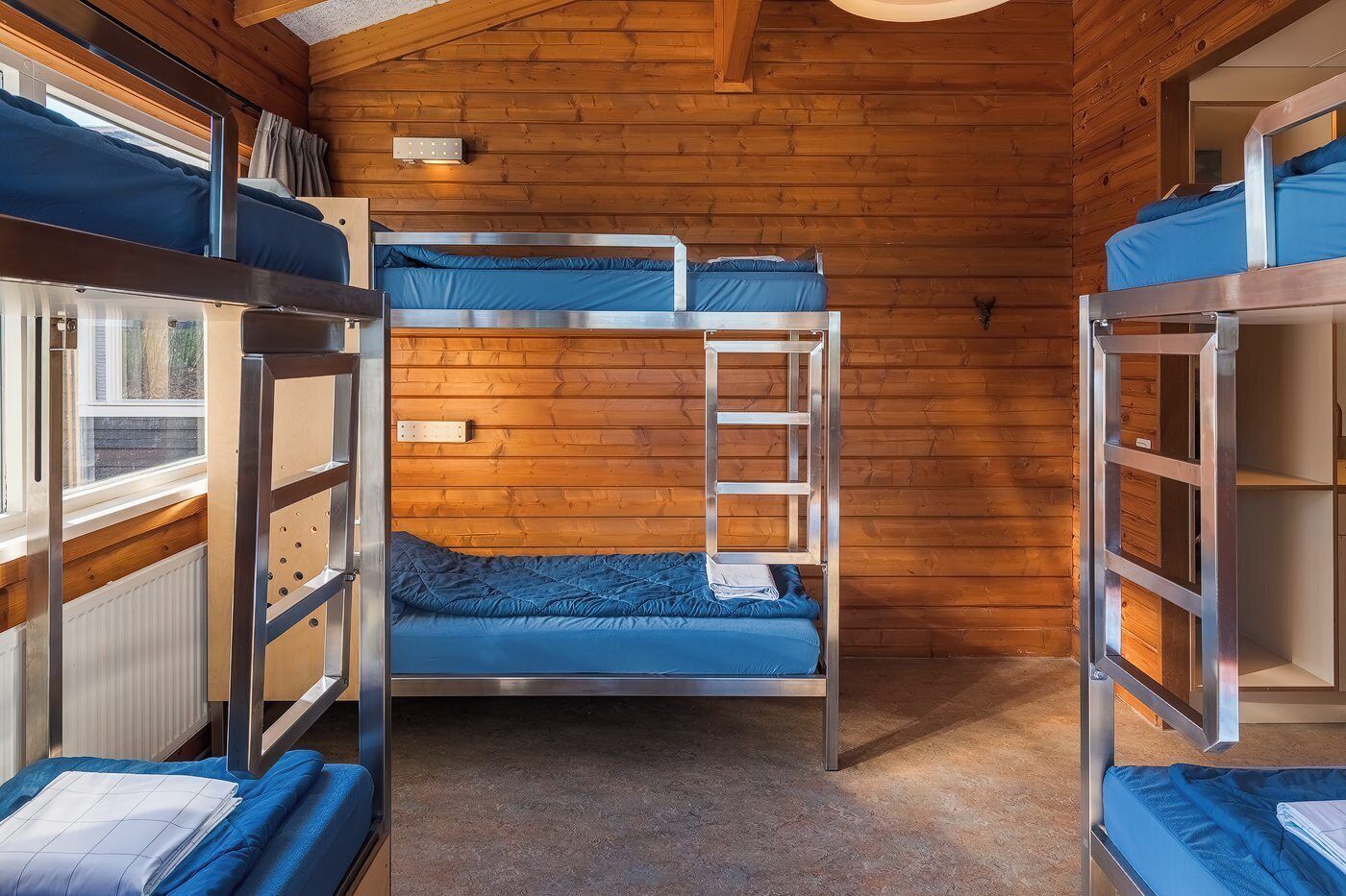 Une chambre avec un lit superposé, des murs en bois, une échelle et une fenêtre.