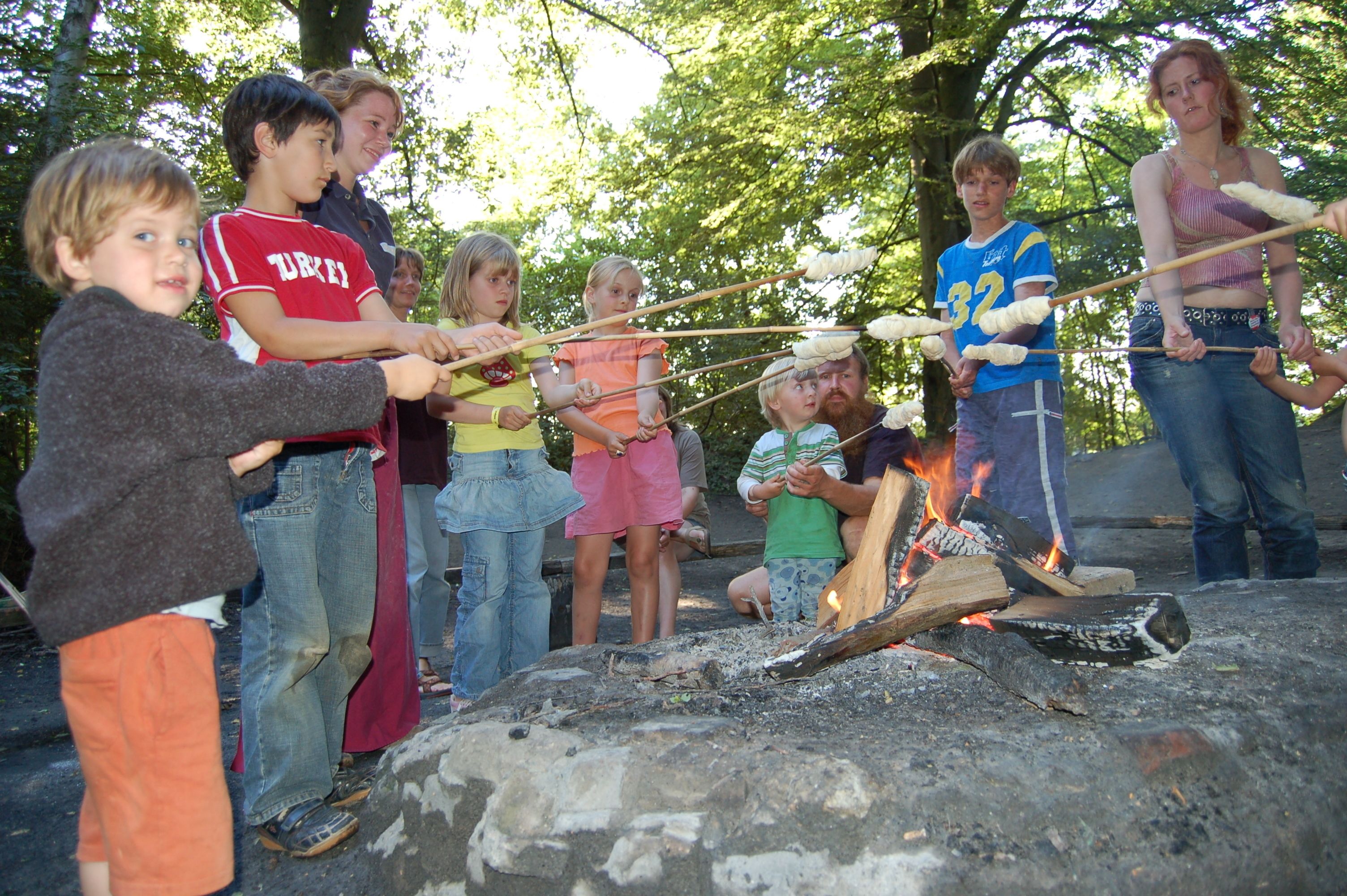 A group of people around a campfire with a rock in the foreground.